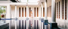 Woman in Sri Lankan dress walking past an indoor water fountain in a room filled with white pillars