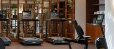 Treadmills with screens in a gym with wooden furnishings and spotlights