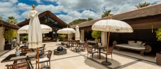 Sunny outdoor courtyard with tables, chairs and bohemian-style ivory umbrellas