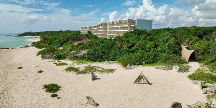 Beachfront at Palmaïa – The House of AïA Milky sands and mangroves in front of a white high-rise resort