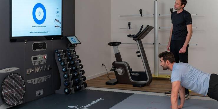 A male guests is having an analysis done with the health coach while doing a push up 