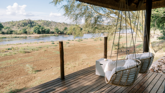 Wooden deck with white-cushioned hanging chairs overlooking a grassy bank and Olifants River