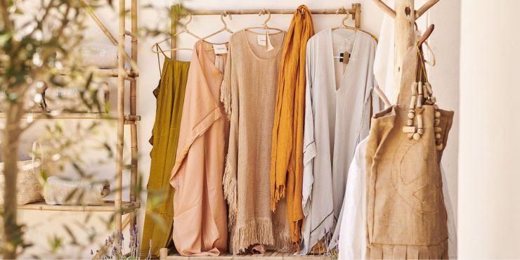 A wooden rack hung with light, bohemian-style clothing including linen kaftans