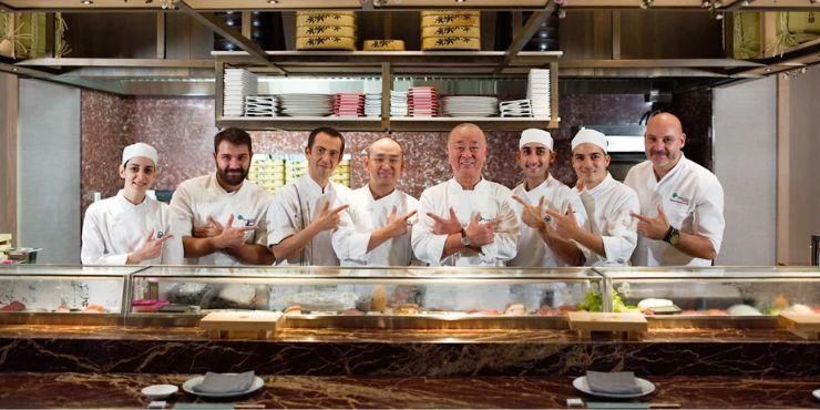 Stylish restaurant with low lighting, black leather seating, grey marble tables and an open kitchen with chefs